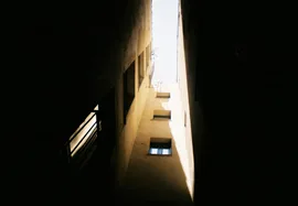 Photo looking up, skywards, between tall buildings on a narrow street in Girona, Catalonia